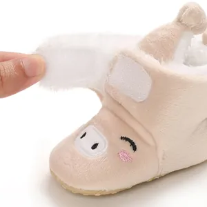 Vue détaillée de bottes en peluche pour bébé avec broderie porcelet et fermeture velcro.
