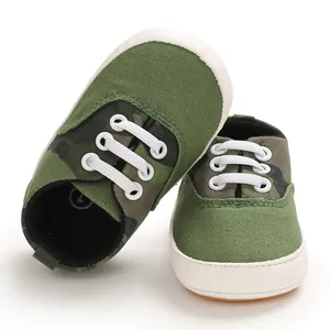 Gros plan de chaussures de marche pour bébé camouflage vert avec semelles en caoutchouc.