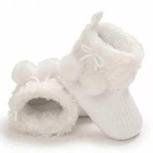 Detail of white fluffy baby booties with cute pompom decorations and soft fur lining