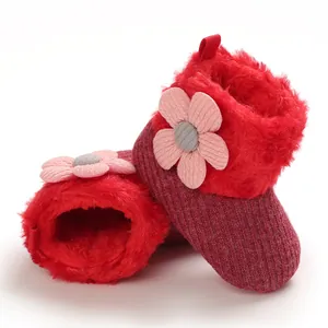 Detailed macro view of red plush infant snow boots featuring cute pink flower applique