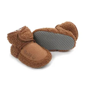 Close-up detail of brown plush baby booties with non-slip rubber soles for infants