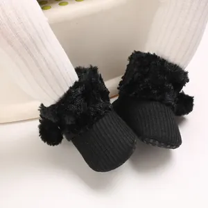 Close-up of black baby girl winter boots featuring soft faux fur trim and cute pom-pom details