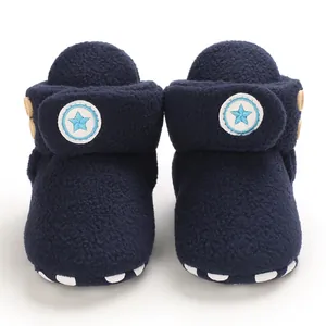 Dettaglio ravvicinato di scarponcini primi passi per neonati in pile blu navy con toppa a stella