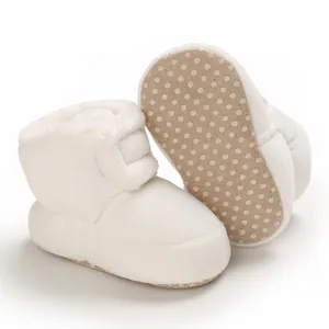Gros plan de bottes de neige blanches pour bébé avec texture velours et semelle antidérapante