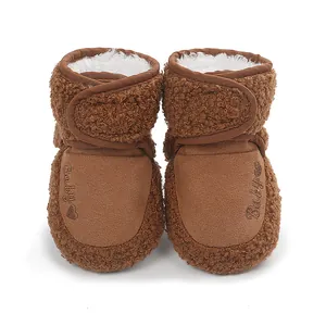 Close-up of warm brown fleece baby winter booties with soft white lining and heart embroidery