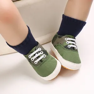 Gros plan de chaussures de marche bébé camouflage vert avec semelles en caoutchouc souple blanc