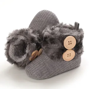 Close-up of grey knit baby snow boots with soft faux fur lining and wooden buttons.
