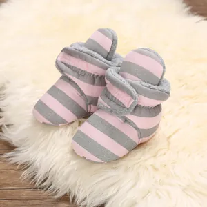Nahaufnahme von gemütlichen rosa-grau gestreiften Babyschuhen mit weichem Fleecefutter