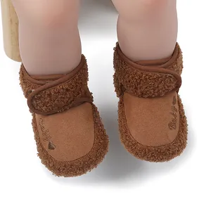 Detailed macro view of brown plush fleece baby winter boots featuring heart embroidery
