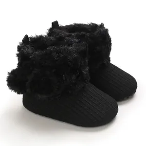Black knitted baby booties with cozy faux fur trim and cute pom-poms for girls
