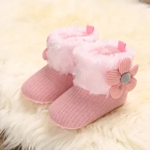 Close-up detail of pink baby winter boots featuring fluffy faux fur and flower accents.