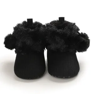 Close-up macro view of cute black baby girl shoes featuring soft plush fur and fluffy pom-poms