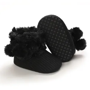 Close-up view of black baby girl shoes featuring fluffy pom-poms and anti-slip soles