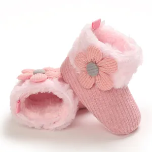 Macro detail of soft pink plush baby boots featuring a knit texture and decorative flower