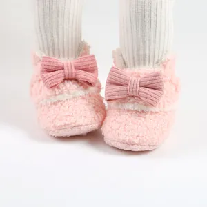 Nahaufnahme rosa flauschige Baby-Winterstiefel mit großer gestrickter Schleife