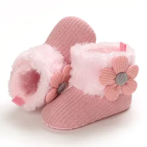 Close-up of pink knitted baby snow boots with soft plush collar and floral detail