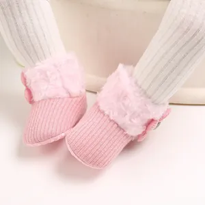 Detailed macro view of pink baby winter fleece boots with soft soles and knit texture