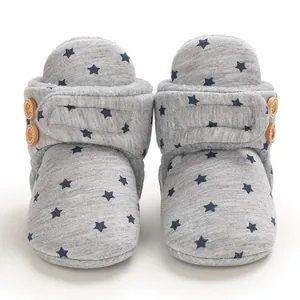 Primer plano de botas de nieve grises para bebé con estrellas azules y botones de madera suave