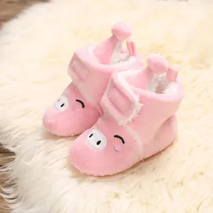 Gros plan sur des bottes de neige roses pour bébé avec broderie mignonne de cochon.