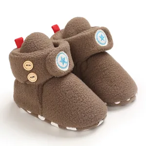 Primo piano di stivaletti neonato in peluche marrone con stella e bottoni in legno.
