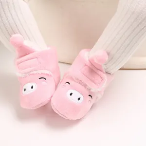 Gros plan sur des bottines en peluche rose pour bébé avec un visage de cochon mignon