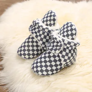 Warm checkered baby winter boots with soft fleece lining on a white fluffy rug