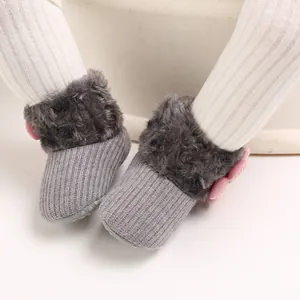 Detailed view of grey knitted baby snow boots with soft plush fur and pink bow detail