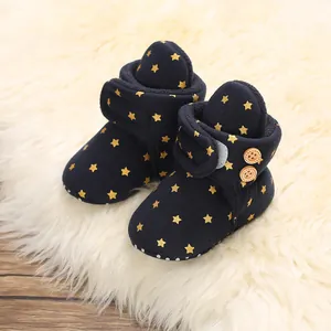Botas de nieve para bebé azul marino con estrellas doradas sobre alfombra suave