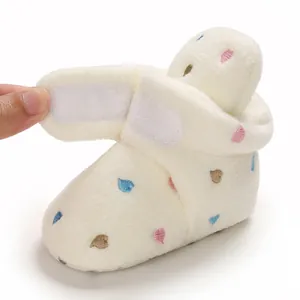 Detail of soft white fleece baby bootie with embroidered hearts and Velcro closure