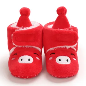 Gros plan de jolies bottines de neige rouges en peluche pour bébé avec visage de cochon mignon