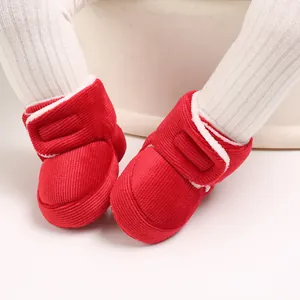 Gros plan de bottes d'hiver pour bébé en velours côtelé rouge avec doublure en polaire blanche.