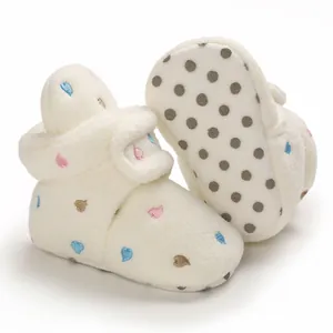 Detailed view of warm white baby fleece booties with heart embroidery and anti-slip sole