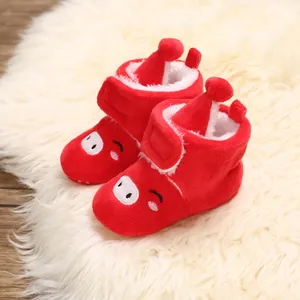 Gros plan sur les bottes de neige pour bébé en peluche rouge avec broderie cochon mignonne.