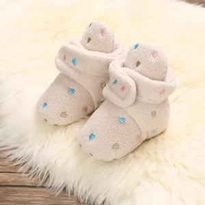 Close-up of cozy cream fleece baby winter boots with colorful embroidered heart patterns