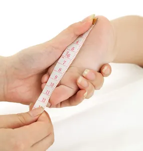 Gros plan détaillé montrant comment mesurer le pied d'un bébé avec un ruban à mesurer souple