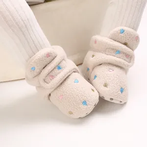 Close-up of soft plush baby winter boots with colorful heart embroidery details.