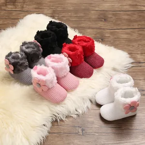 Close-up of assorted fleece-lined baby winter boots with decorative floral accents and soft soles.