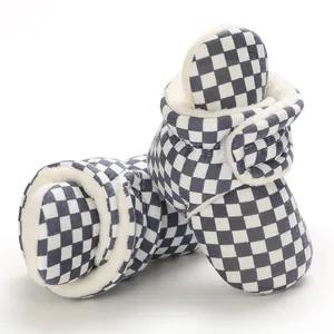 Close-up detail of fleece-lined checkered baby winter booties with warm soft soles for infants