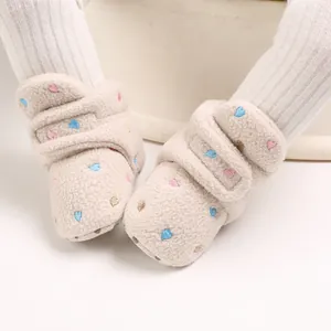 Close-up of warm beige baby fleece snow boots with colorful heart embroidery details.
