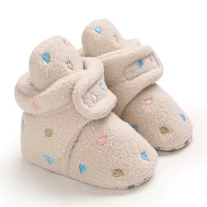 Close-up of cozy beige baby winter boots with colorful embroidered heart patterns