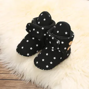 Primer plano de botas de nieve negras para bebé con estrellas y forro polar