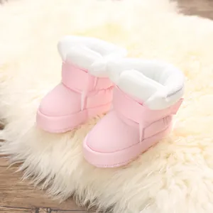 Zachte roze babyschoentjes met warme pluche voering op een luxe wit faux-bont kleedje