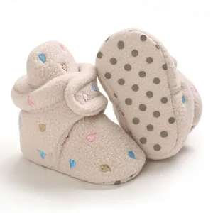 Detailed view of beige fleece baby snow boots with embroidered hearts and anti-slip sole