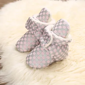 Detailed macro view of pink checkerboard baby snow boots with soft white plush lining.