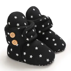 Vista detallada de botas de invierno negras para bebé con estrellas blancas y forro polar