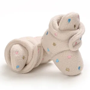 Close-up of beige baby fleece booties with embroidered colorful heart patterns for winter