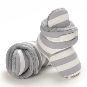 Nahaufnahme von grau-weiß gestreiften warmen Fleece-Babyschuhen mit rutschfester Sohle