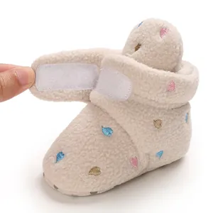 Detail view of cream baby fleece bootie with a Velcro strap and heart embroidery.