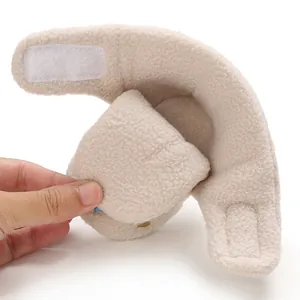 Detailed view of a soft beige fleece baby bootie featuring an adjustable Velcro strap closure