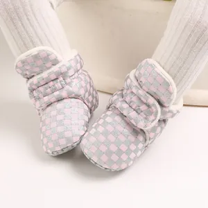 Close-up of pink and silver checkered baby winter boots with soft plush white lining
